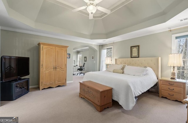 bedroom with multiple windows, a raised ceiling, arched walkways, and light colored carpet