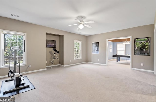 workout room featuring a wealth of natural light, visible vents, and light colored carpet