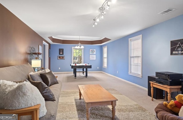 living area with a raised ceiling, carpet flooring, baseboards, and visible vents