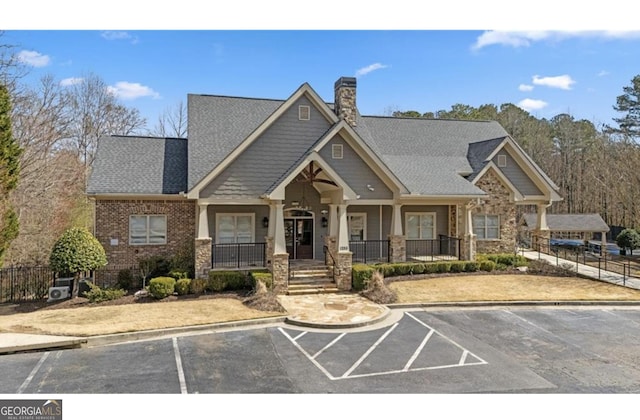 view of front of property featuring fence, uncovered parking, covered porch, a chimney, and brick siding