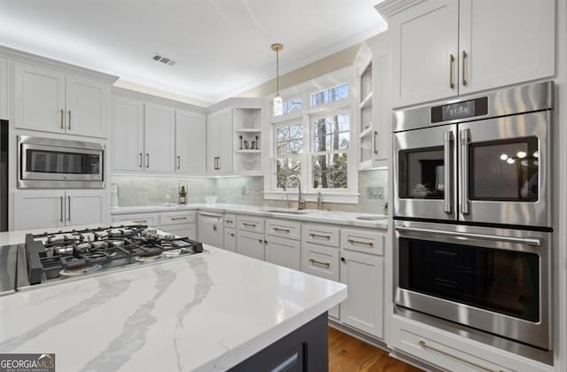 kitchen featuring open shelves, backsplash, appliances with stainless steel finishes, and a sink