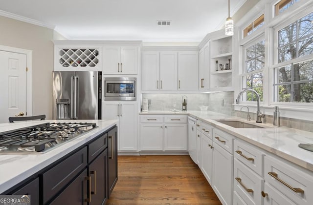 kitchen featuring visible vents, crown molding, appliances with stainless steel finishes, white cabinets, and a sink