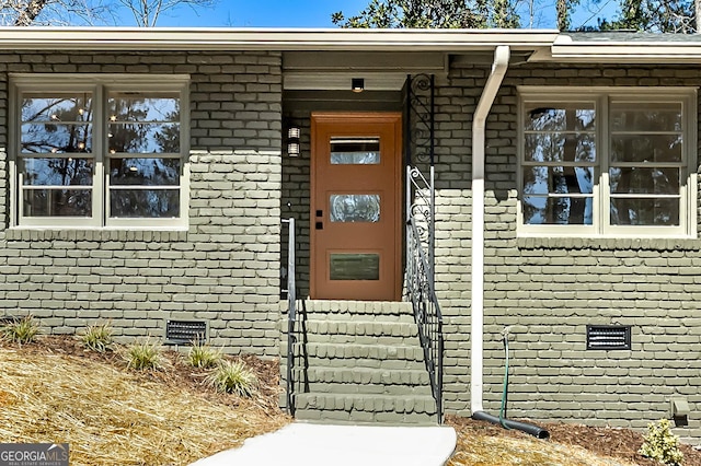 doorway to property featuring crawl space and brick siding