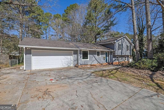 split level home featuring driveway, an attached garage, and fence