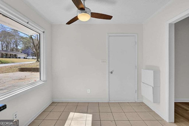 spare room featuring light tile patterned flooring, ceiling fan, and baseboards