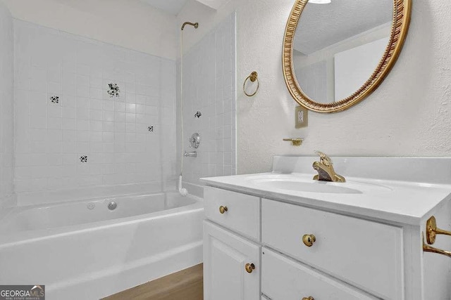 bathroom featuring bathing tub / shower combination, vanity, and a textured wall