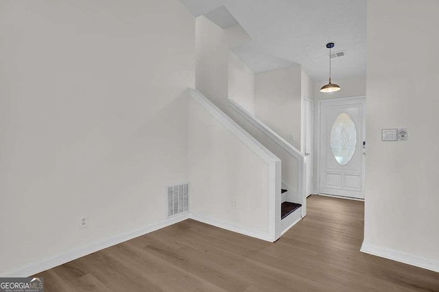 foyer featuring stairs, visible vents, baseboards, and wood finished floors