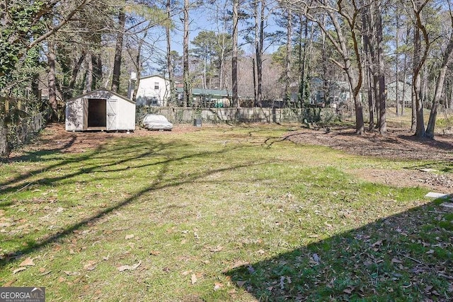 view of yard featuring a storage shed, fence, and an outbuilding