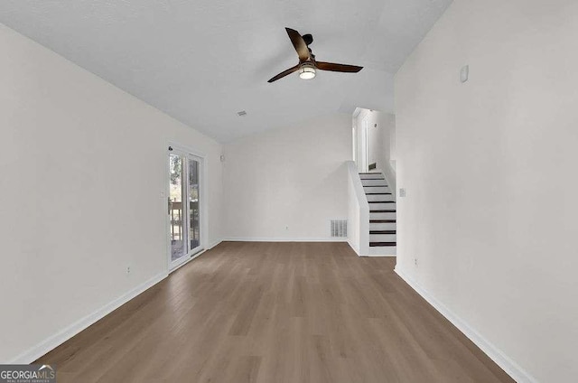 unfurnished living room featuring visible vents, stairway, vaulted ceiling, wood finished floors, and baseboards