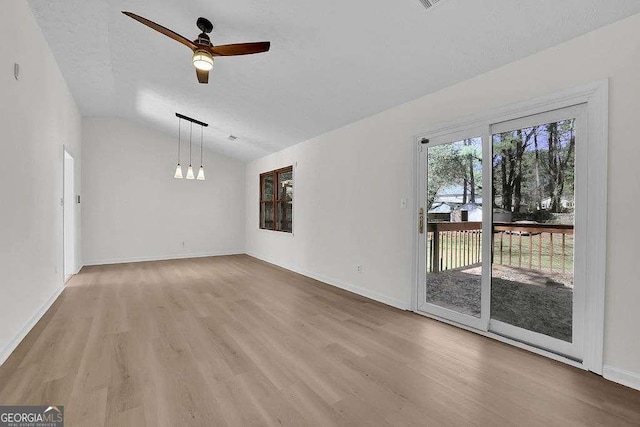 unfurnished living room with a textured ceiling, wood finished floors, a ceiling fan, baseboards, and vaulted ceiling