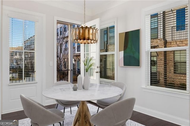 dining area featuring a wealth of natural light, dark wood-style flooring, a notable chandelier, and baseboards