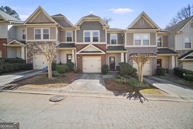 multi unit property featuring concrete driveway, brick siding, board and batten siding, and an attached garage