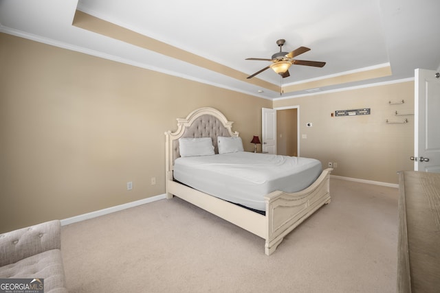 bedroom with a tray ceiling, light colored carpet, and baseboards