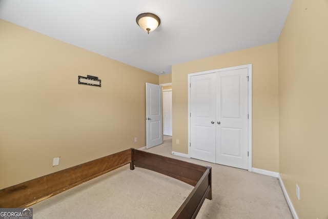 carpeted bedroom featuring baseboards and a closet