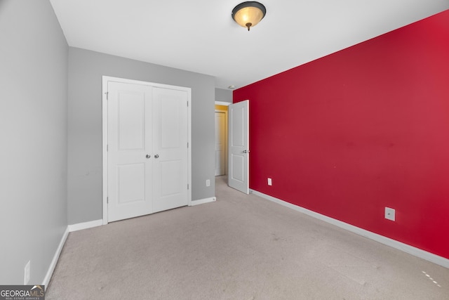 unfurnished bedroom with a closet, carpet flooring, and baseboards