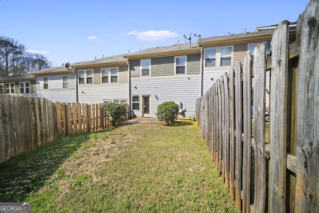 rear view of house with a fenced backyard and a yard