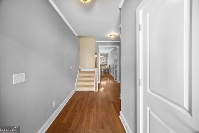 corridor featuring stairs, ornamental molding, baseboards, and wood finished floors