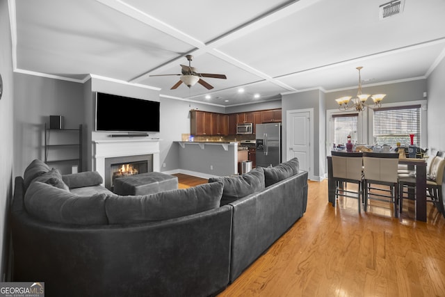 living room featuring light wood-style flooring, coffered ceiling, visible vents, a lit fireplace, and crown molding