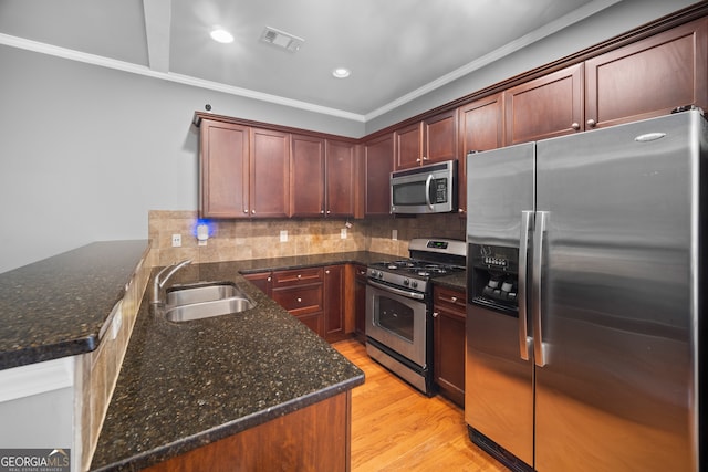 kitchen featuring stainless steel appliances, visible vents, decorative backsplash, a sink, and light wood-type flooring