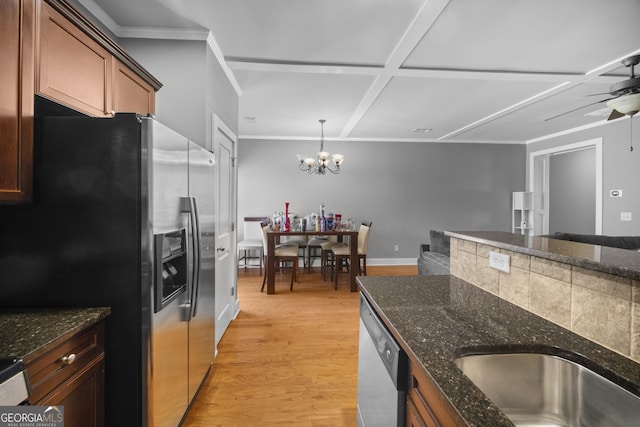 kitchen with dark stone counters, light wood-style flooring, appliances with stainless steel finishes, pendant lighting, and ceiling fan with notable chandelier