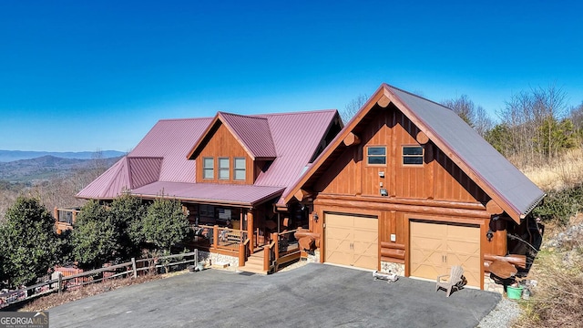 log home featuring metal roof, aphalt driveway, a mountain view, covered porch, and a garage