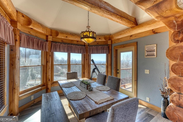 dining area with a textured wall, baseboards, wood finished floors, and beamed ceiling