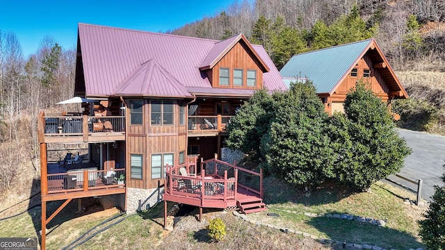 back of house with metal roof, a deck, and a balcony