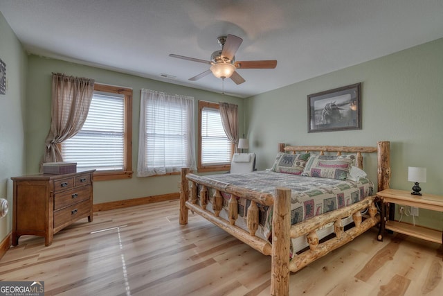 bedroom with ceiling fan, light wood-type flooring, visible vents, and baseboards