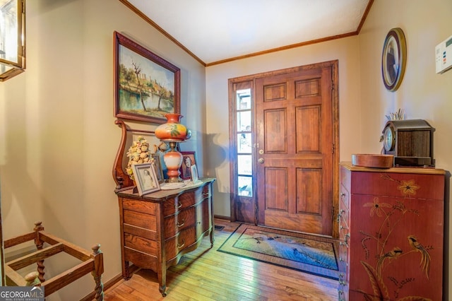 foyer entrance featuring light wood-style flooring, ornamental molding, and baseboards