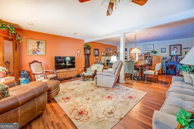 living area with a fireplace, wood finished floors, and a ceiling fan