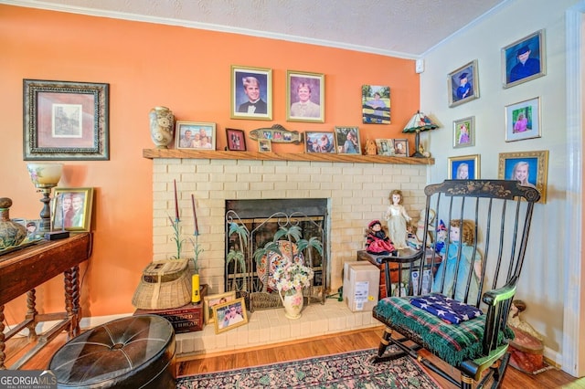 sitting room with a textured ceiling, crown molding, a fireplace, and wood finished floors