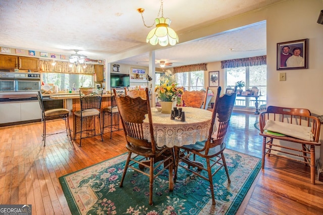 dining space featuring light wood-style floors, ceiling fan, and a textured ceiling