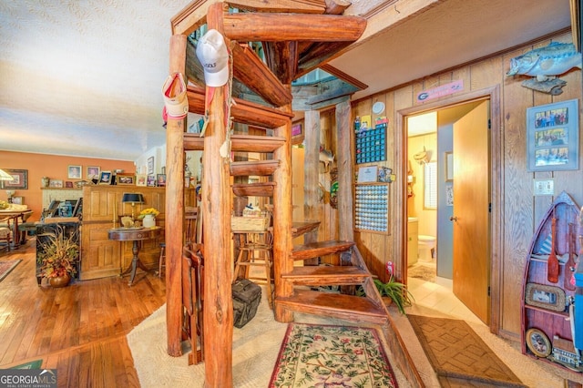 staircase featuring wood walls, a textured ceiling, and wood finished floors