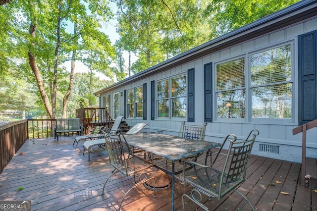 wooden deck featuring outdoor dining area and visible vents