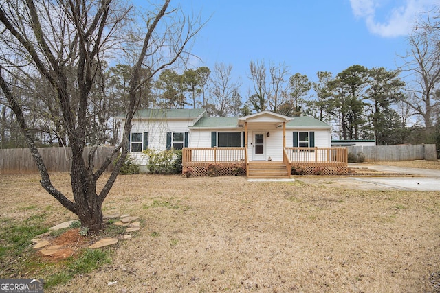 ranch-style house with fence, a deck, and a front yard