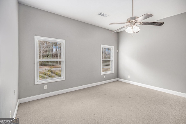 carpeted empty room featuring a ceiling fan, visible vents, and baseboards