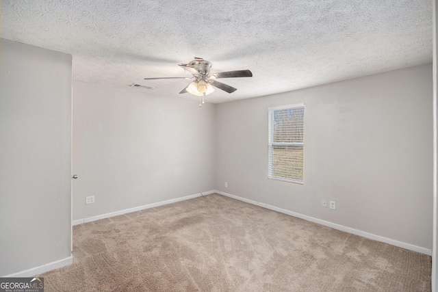 carpeted spare room featuring a ceiling fan, visible vents, a textured ceiling, and baseboards