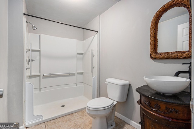 bathroom with tile patterned flooring, toilet, vanity, baseboards, and walk in shower