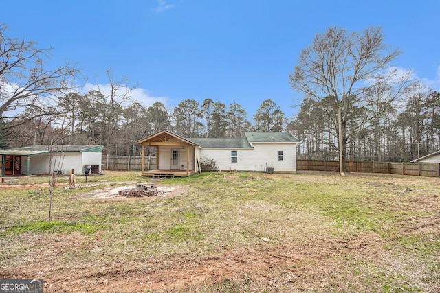 rear view of property with an outbuilding, a lawn, an outdoor fire pit, a deck, and a fenced backyard