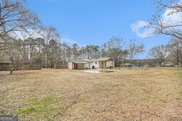 view of yard featuring a garage, an outdoor fire pit, and fence