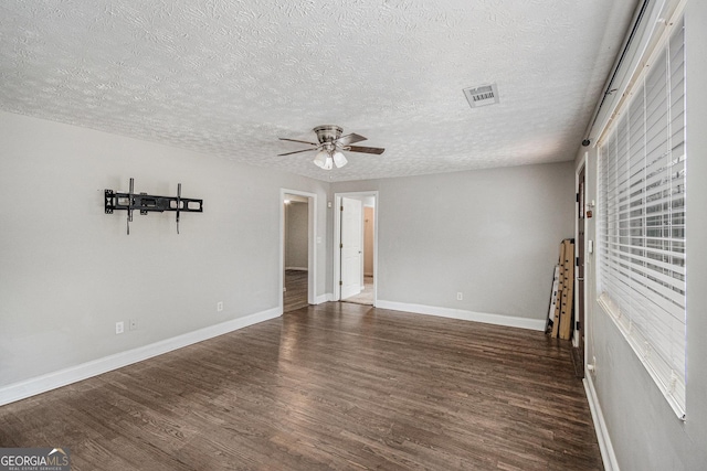 empty room with baseboards, visible vents, ceiling fan, wood finished floors, and a textured ceiling