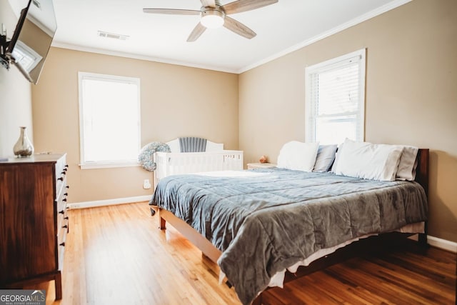 bedroom with ornamental molding, multiple windows, wood finished floors, and visible vents