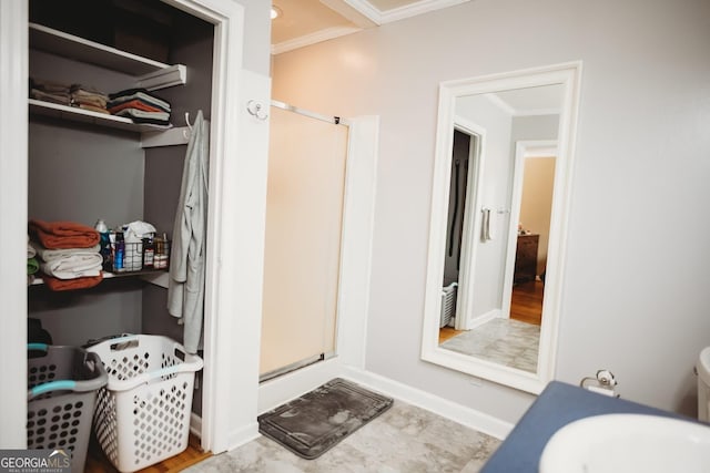 bathroom with a shower stall, baseboards, and crown molding