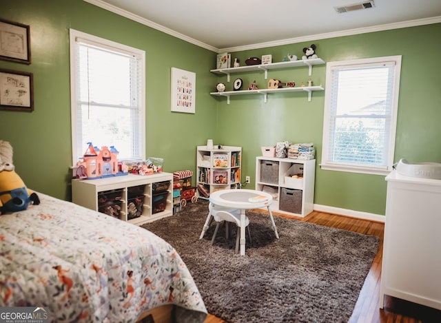 bedroom with ornamental molding, visible vents, baseboards, and wood finished floors