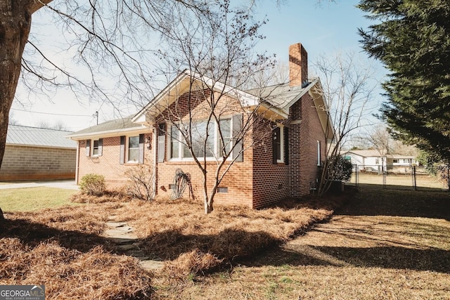 view of side of property with crawl space, a chimney, fence, and brick siding