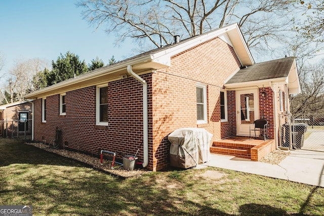 view of property exterior featuring brick siding, fence, and a yard