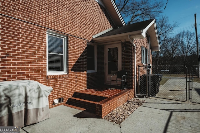 view of property exterior with crawl space, a gate, and brick siding