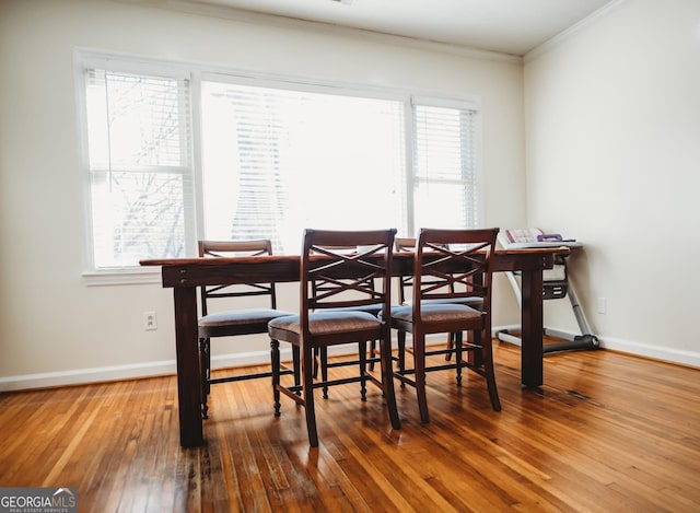 dining area with hardwood / wood-style flooring, baseboards, and ornamental molding