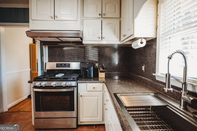 kitchen featuring stainless steel gas range, range hood, a wealth of natural light, and a sink