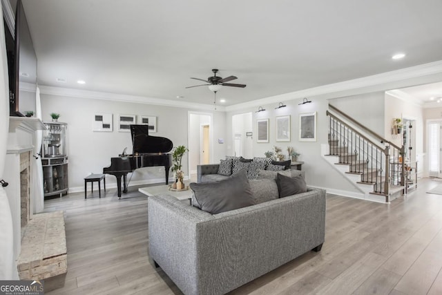 living area featuring baseboards, a fireplace with raised hearth, stairway, ornamental molding, and light wood-type flooring